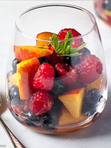 A dessert glass filled with nectarines and berries in Prosecco.