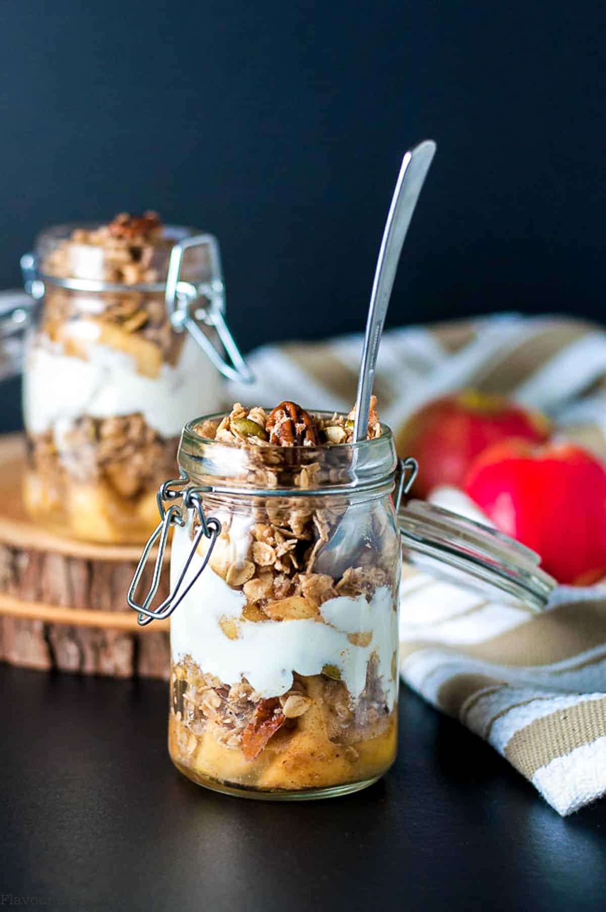 A jar with apple crumble breakfast parfait with layers of caramelized apples, yogurt and granola.