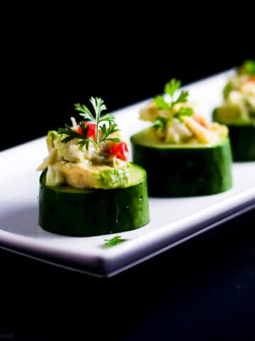 Crab stuffed cucumber cups on a white platter.