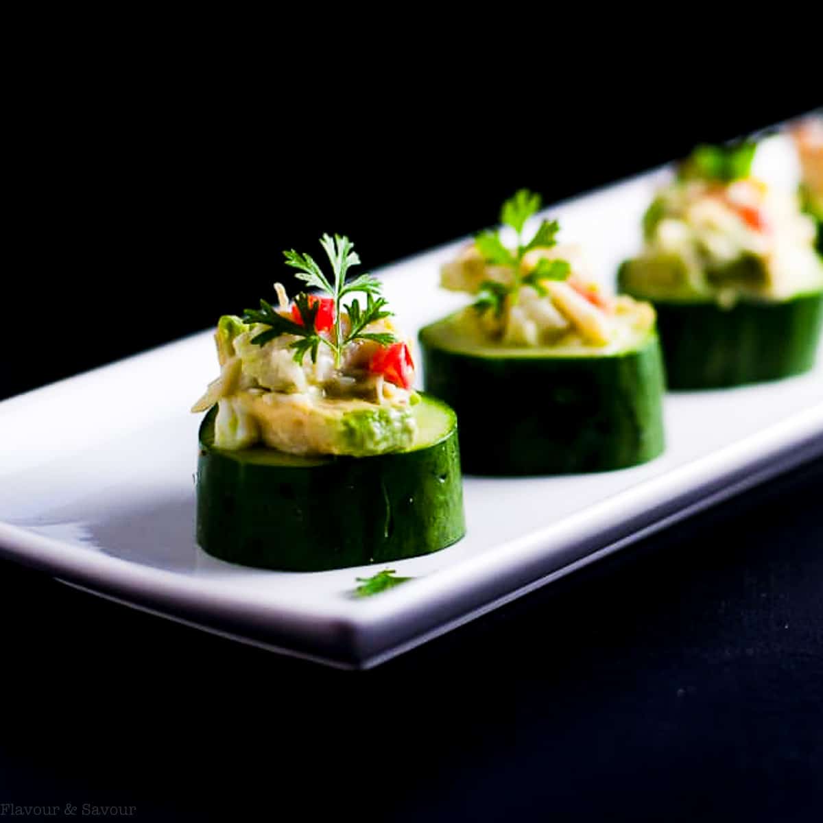 Crab stuffed cucumber cups garnished with cilantro leaves.