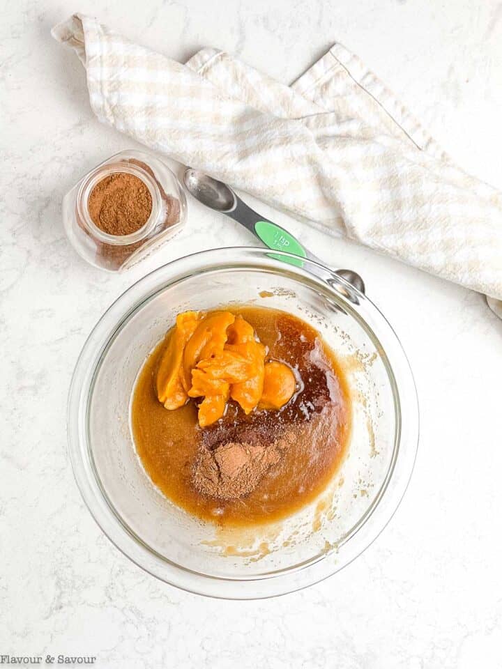 Adding pumpkin and vanilla to sugar and butter mixture for pumpkin pecan cookies.