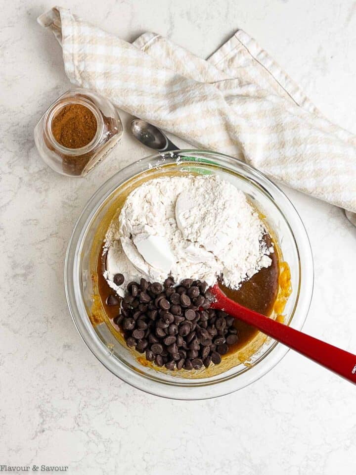 Adding flour and chocolate chips to cookie batter.