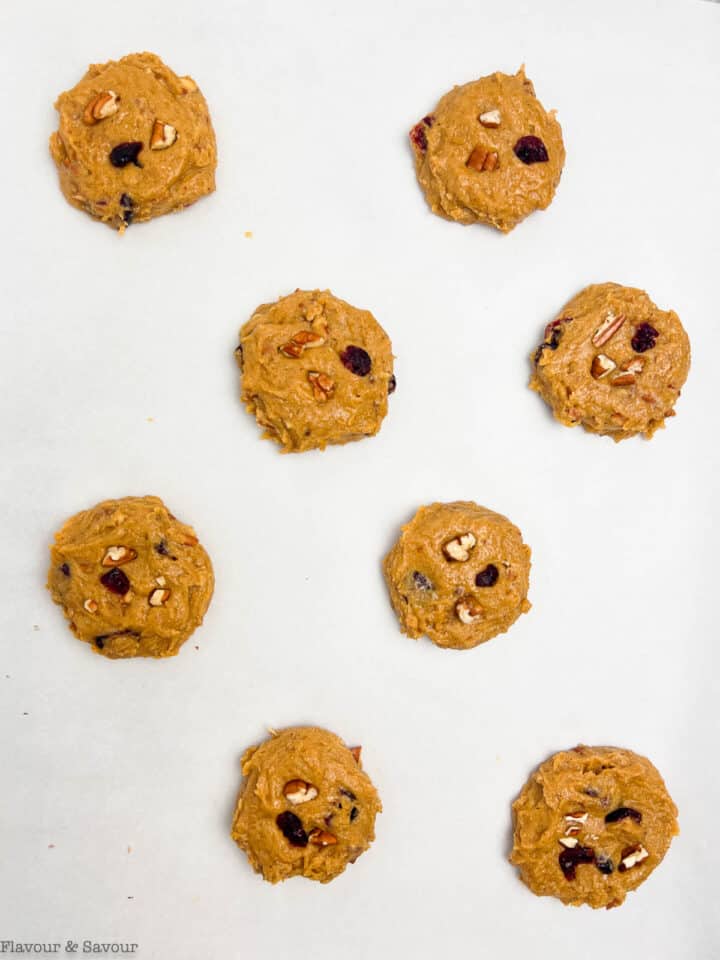 Cookie dough balls arranged on a baking sheet.