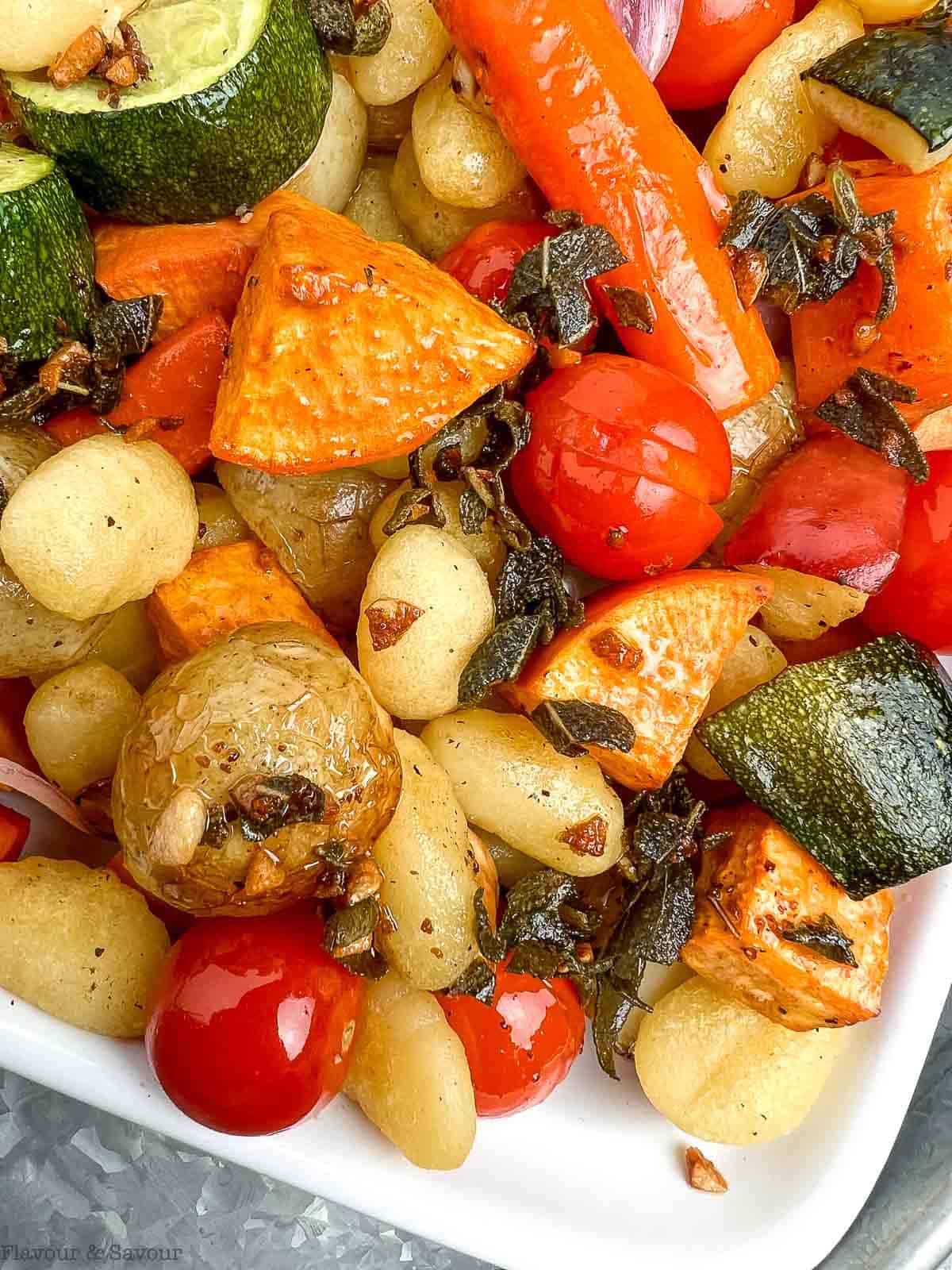 Close up view of roasted vegetables and gnocchi drizzled with browned butter sage sauce.