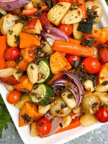 Overhead view of roasted gnocchi and fall vegetables on a large white platter.