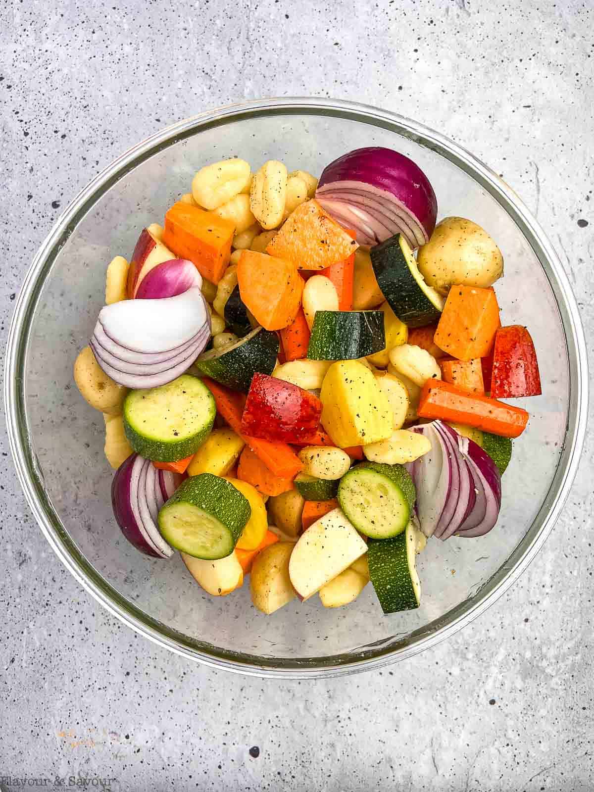 Colourful vegetables and gluten-free gnocchi in a glass bowl with olive oil.