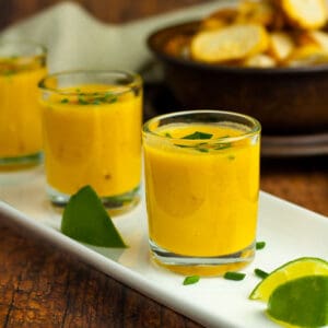 Thai pumpkin soup in shooter glasses on a white tray.