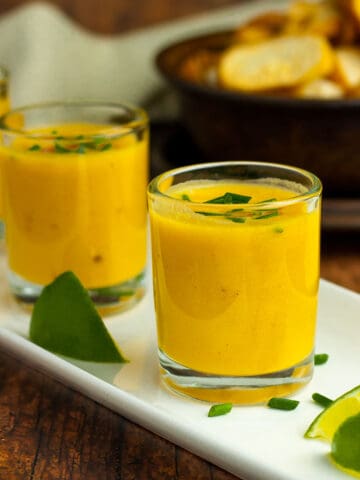 Thai pumpkin soup in shooter glasses on a white tray.