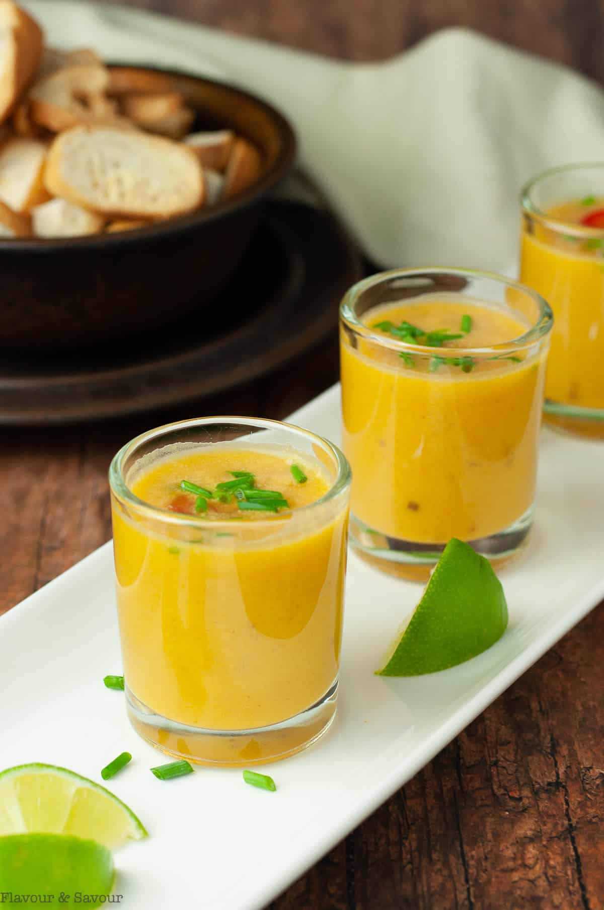 Thai pumpkin soup shots in small glasses on a white tray.