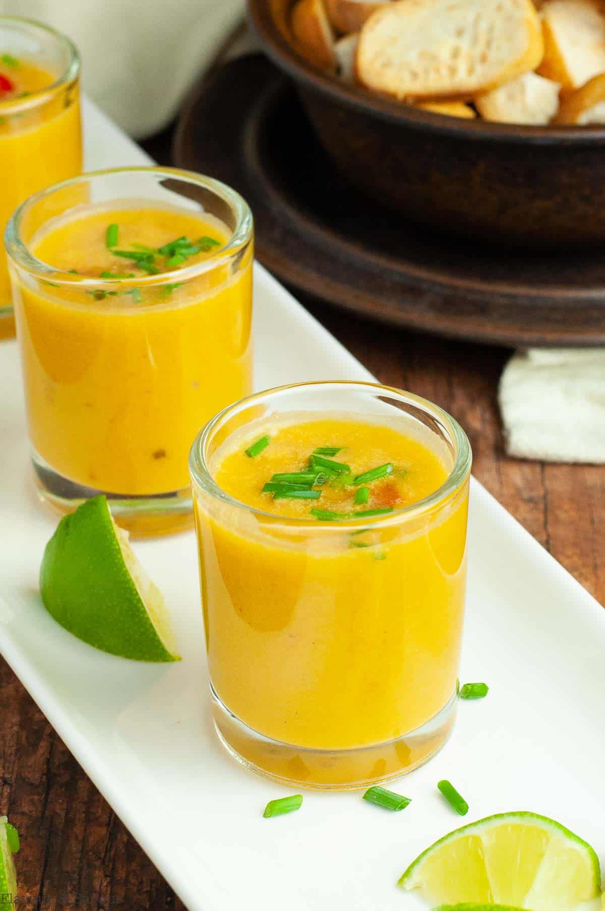 Thai pumpkin curried soup in shot glasses on a white tray.