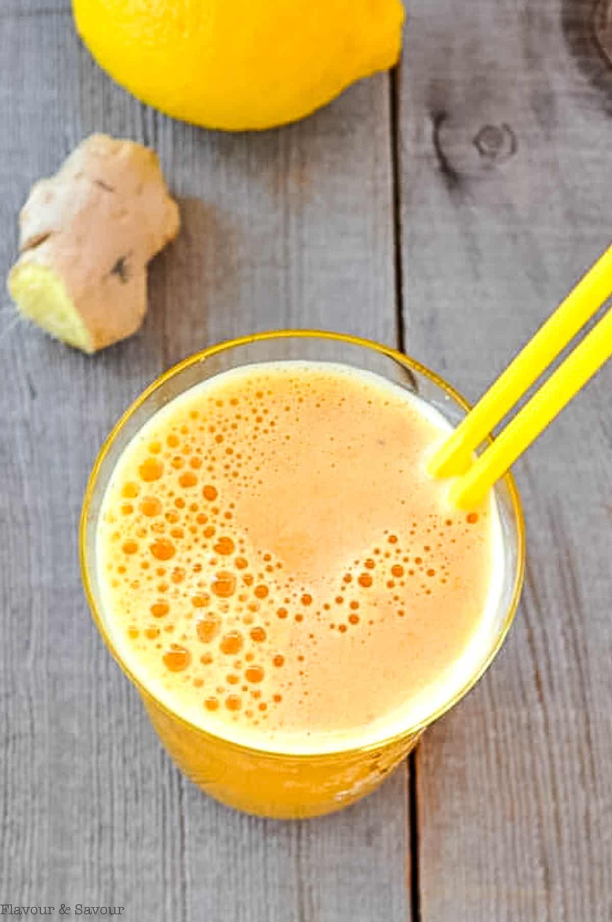 Overhead view of a glass of turmeric tonic with straws.