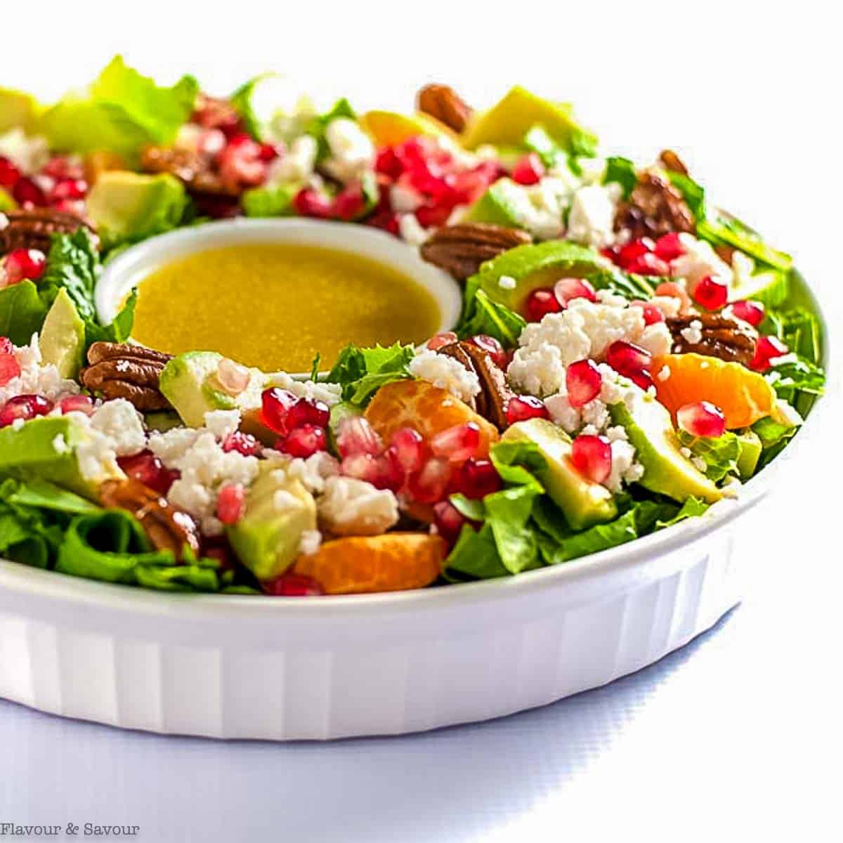 Side view of Christmas Wreath Salad with oranges, pomegranate, avocado and feta.