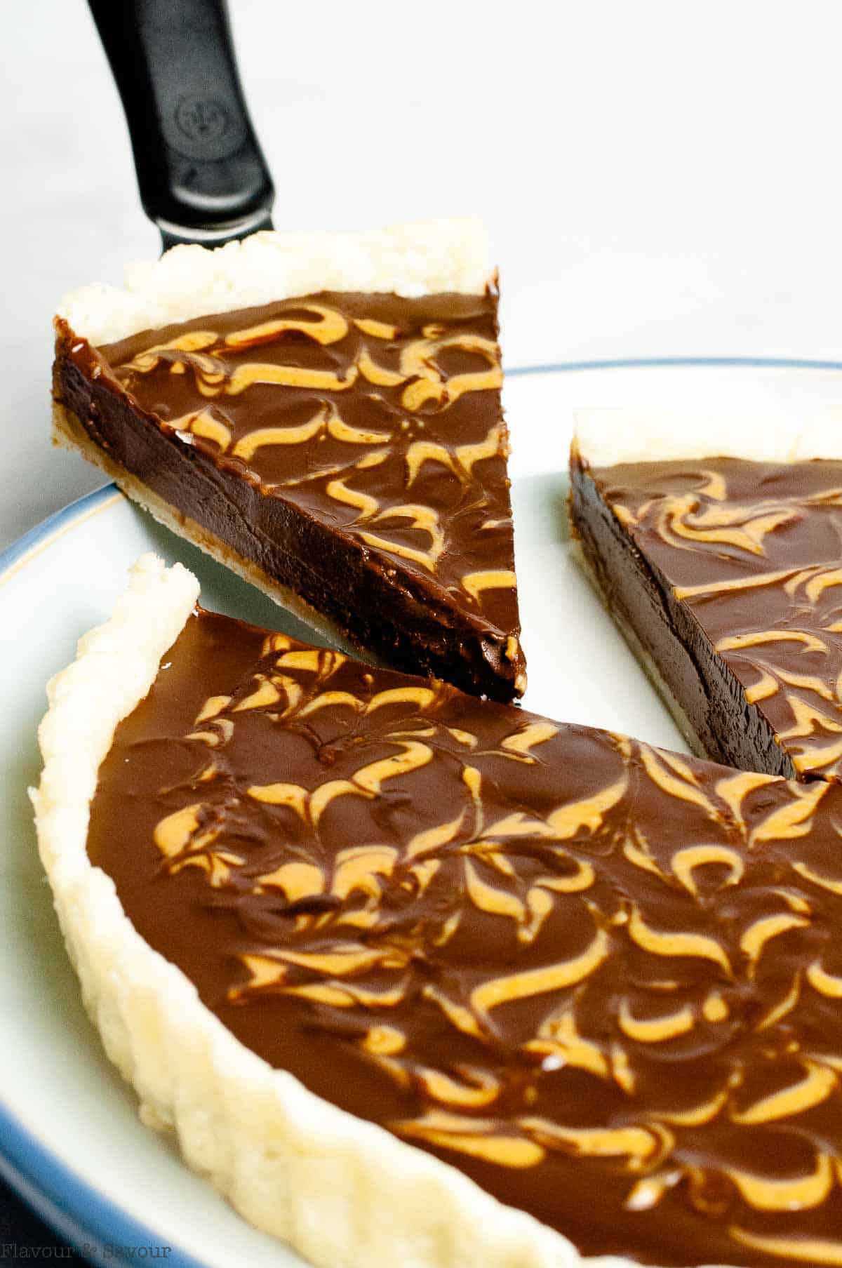 A slice of chocolate peanut butter pie being lifted from a pie.