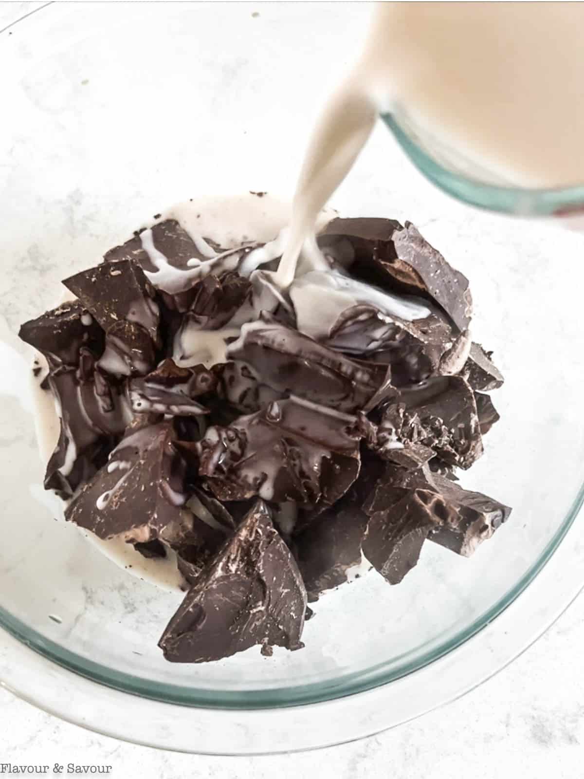 Pouring coconut cream over chocolate to make vegan chocolate ganache.