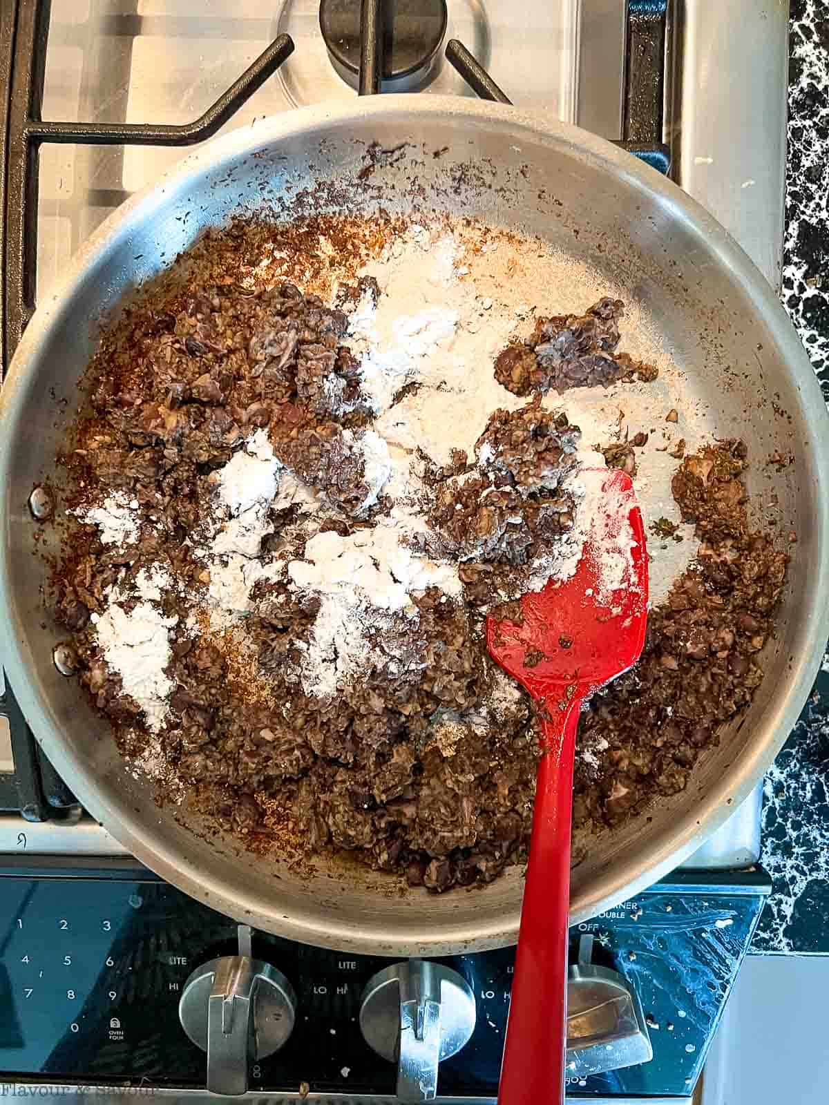 Adding flour and nutritional yeast to black bean burger mixture.