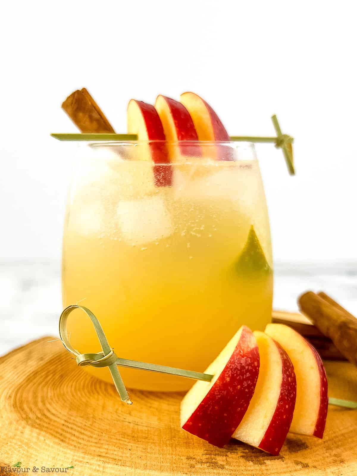 A glass of apple cider ginger beer mocktail garnished with apple slices.