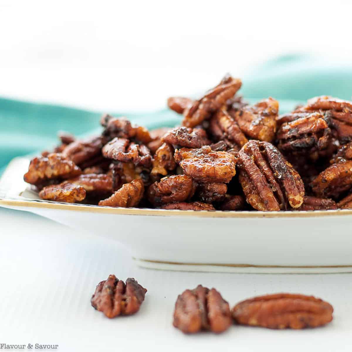 Close up view of a small serving dish of caramel spiced pecans also called candied pecans.