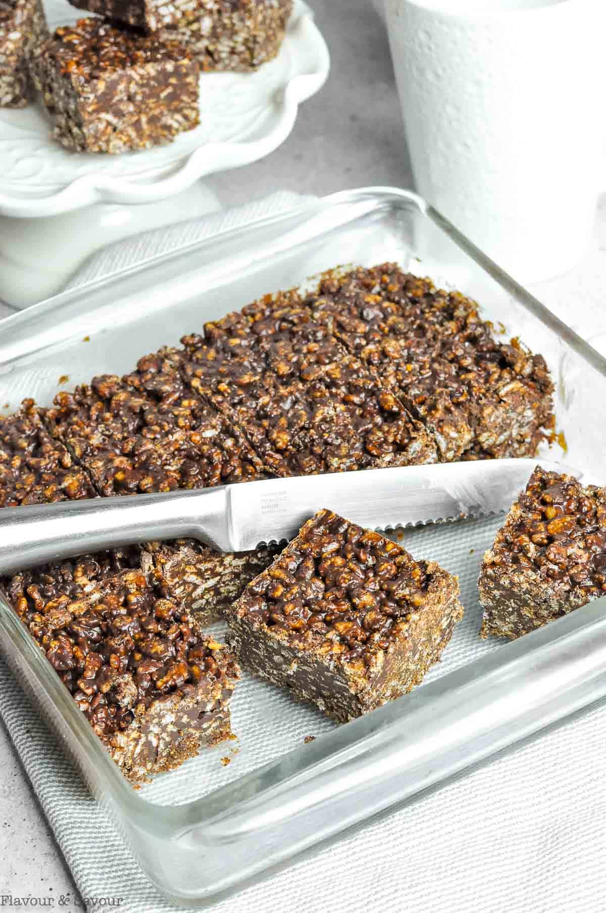 Sliced squares of crisp rice cereal chocolate peanut butter squares in a glass baking dish.