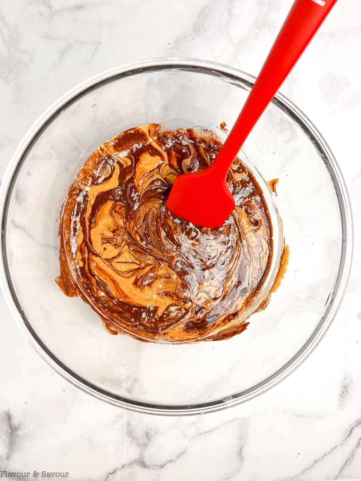 Stirring ingredients for chocolate peanut butter Rice Krispie squares with a spatula.