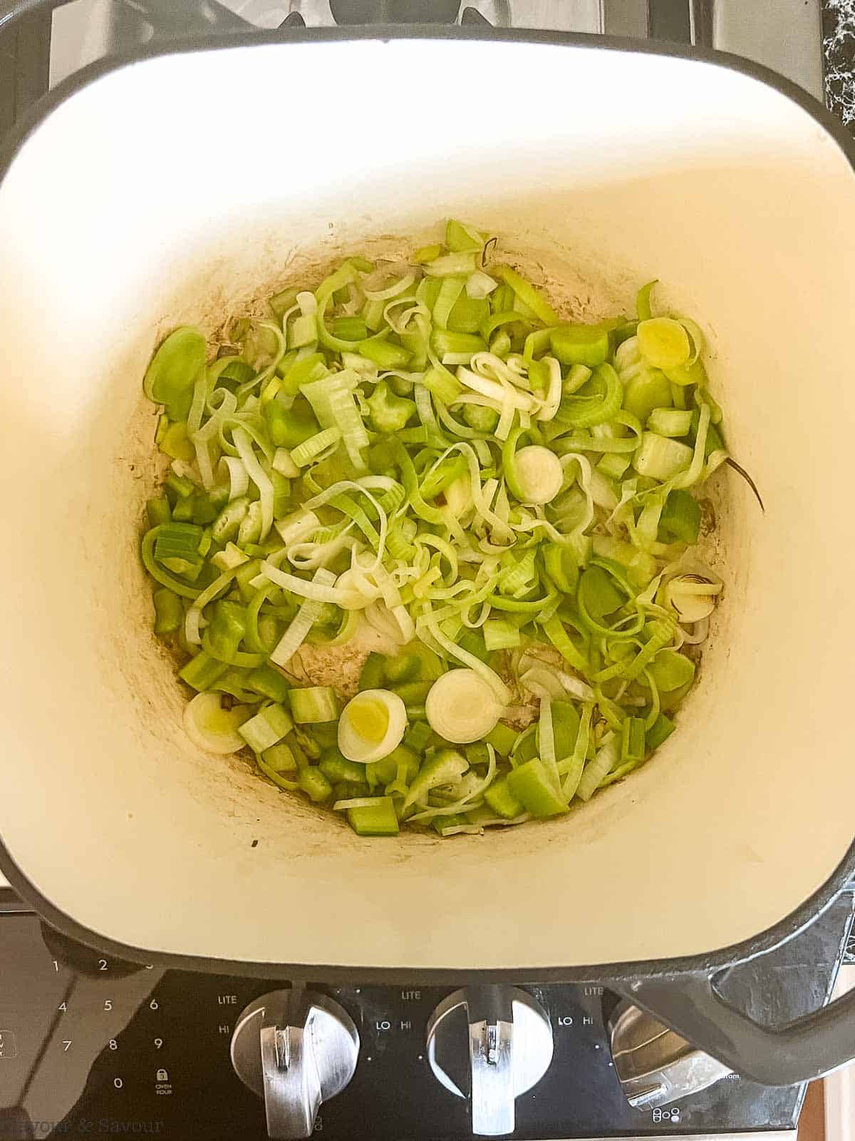 Sautéing leeks and celery in a pot on the stovetop.