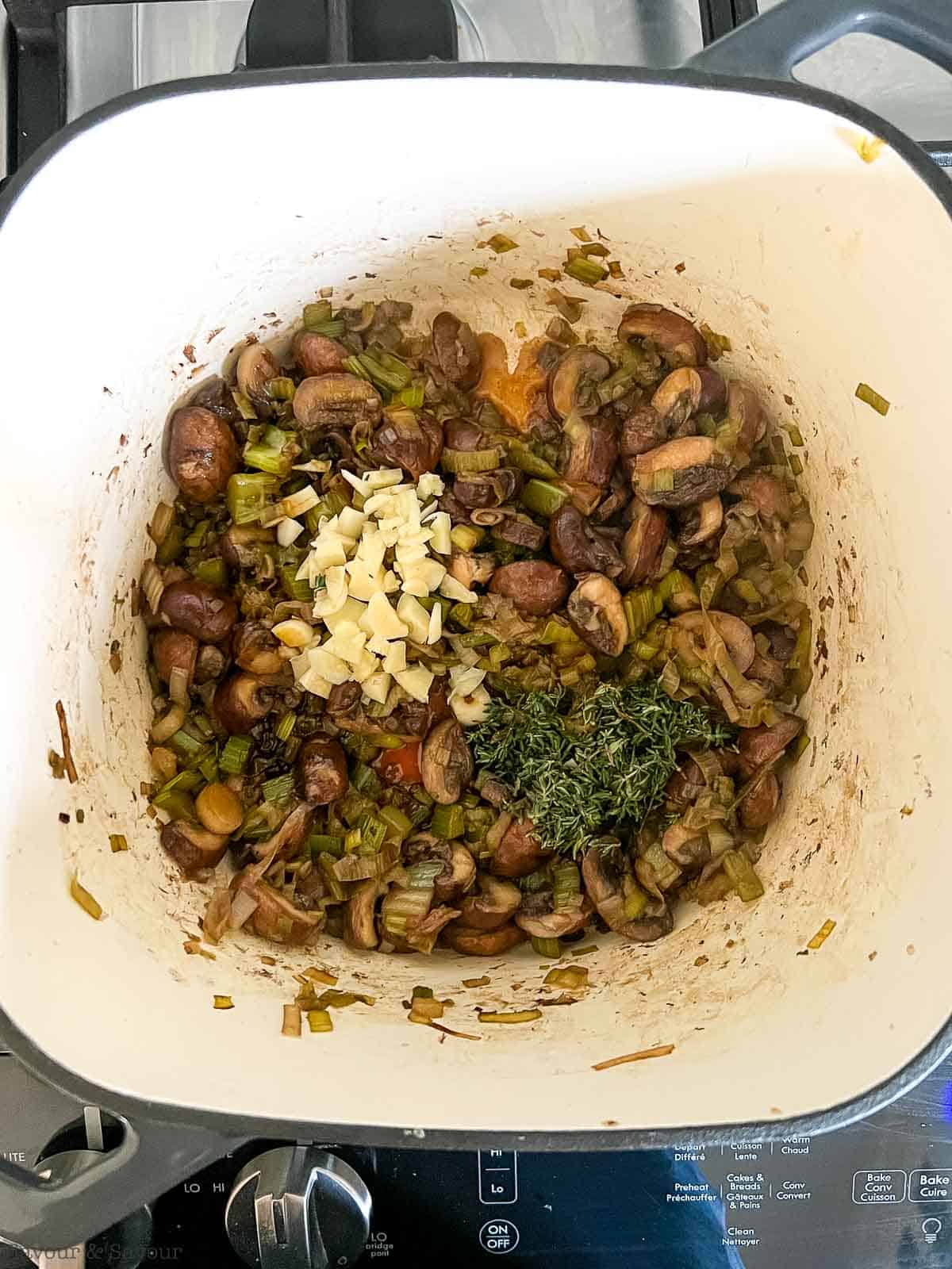 Adding garlic and thyme to sautéed mushrooms.