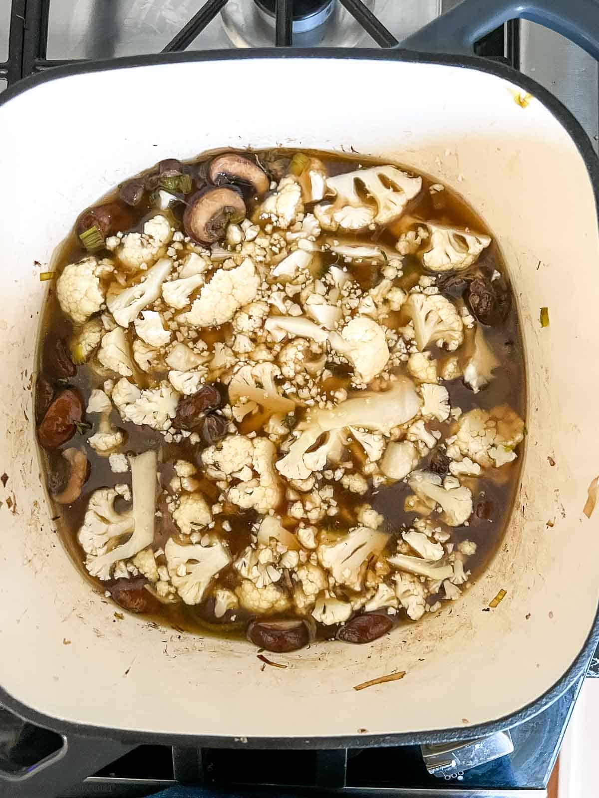 Adding cauliflower and broth to sautéed mushrooms for vegan cream of mushroom soup.