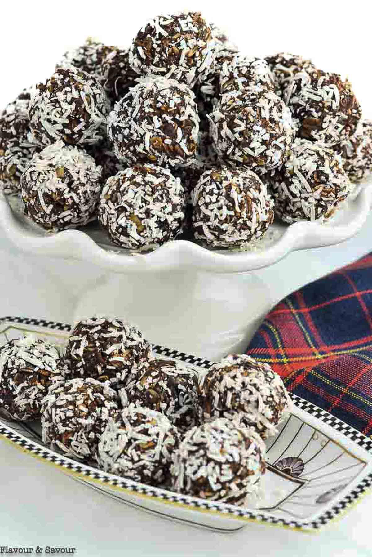 Close up view of chocolate almond snowballs on a cake plate and in a smaller serving dish.