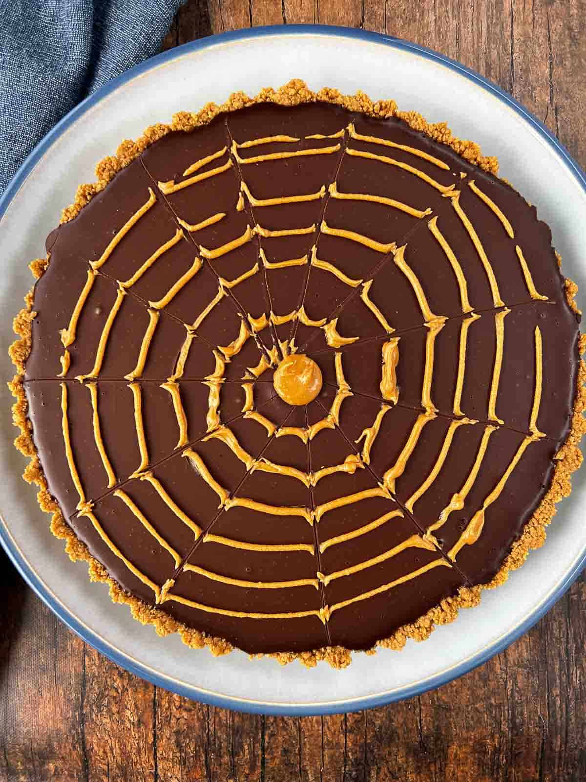 Peanut butter spider web design on chocolate ganache pie.