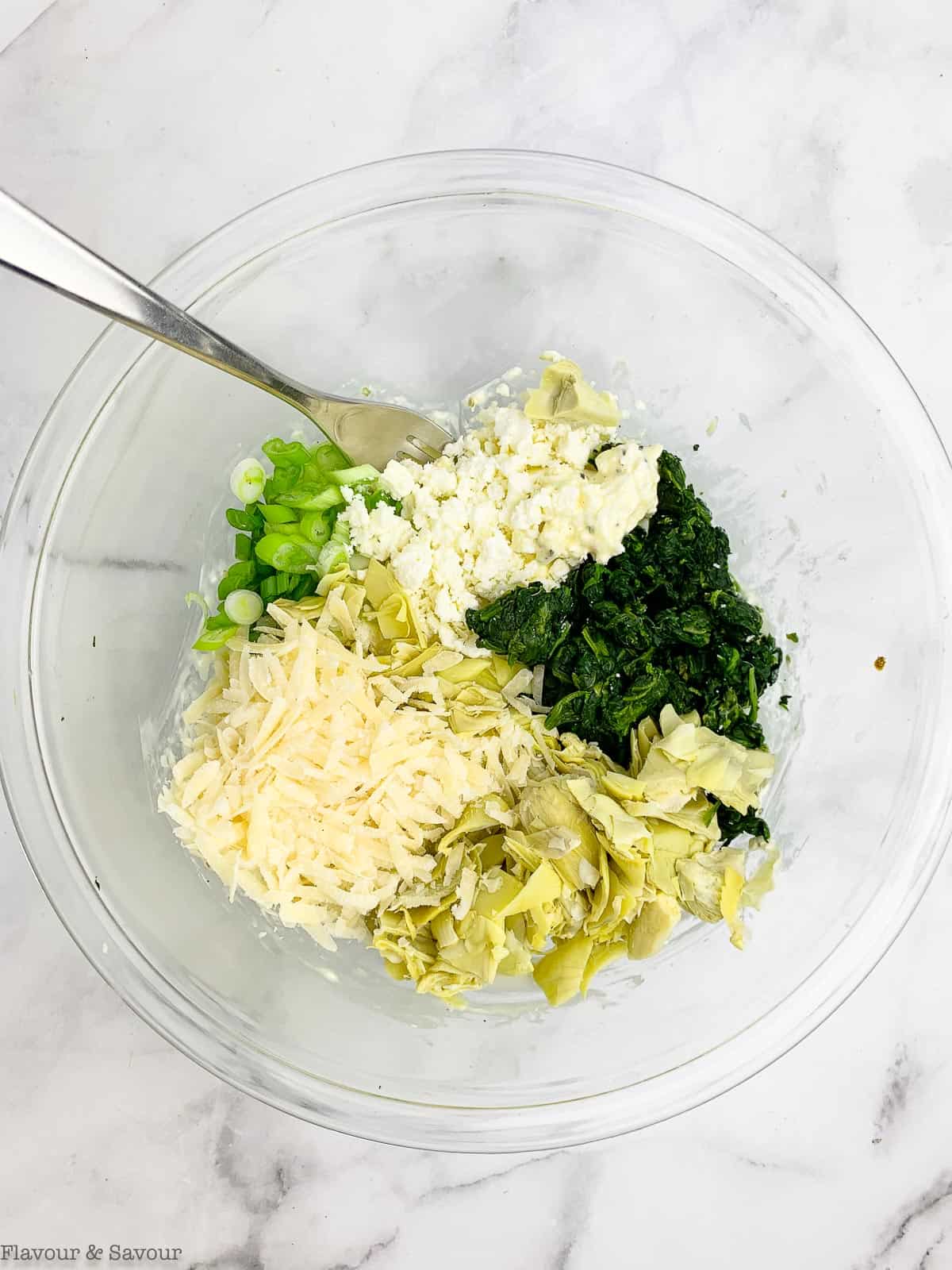 Adding cheese and spinach to a bowl to make the filling for pinwheels.