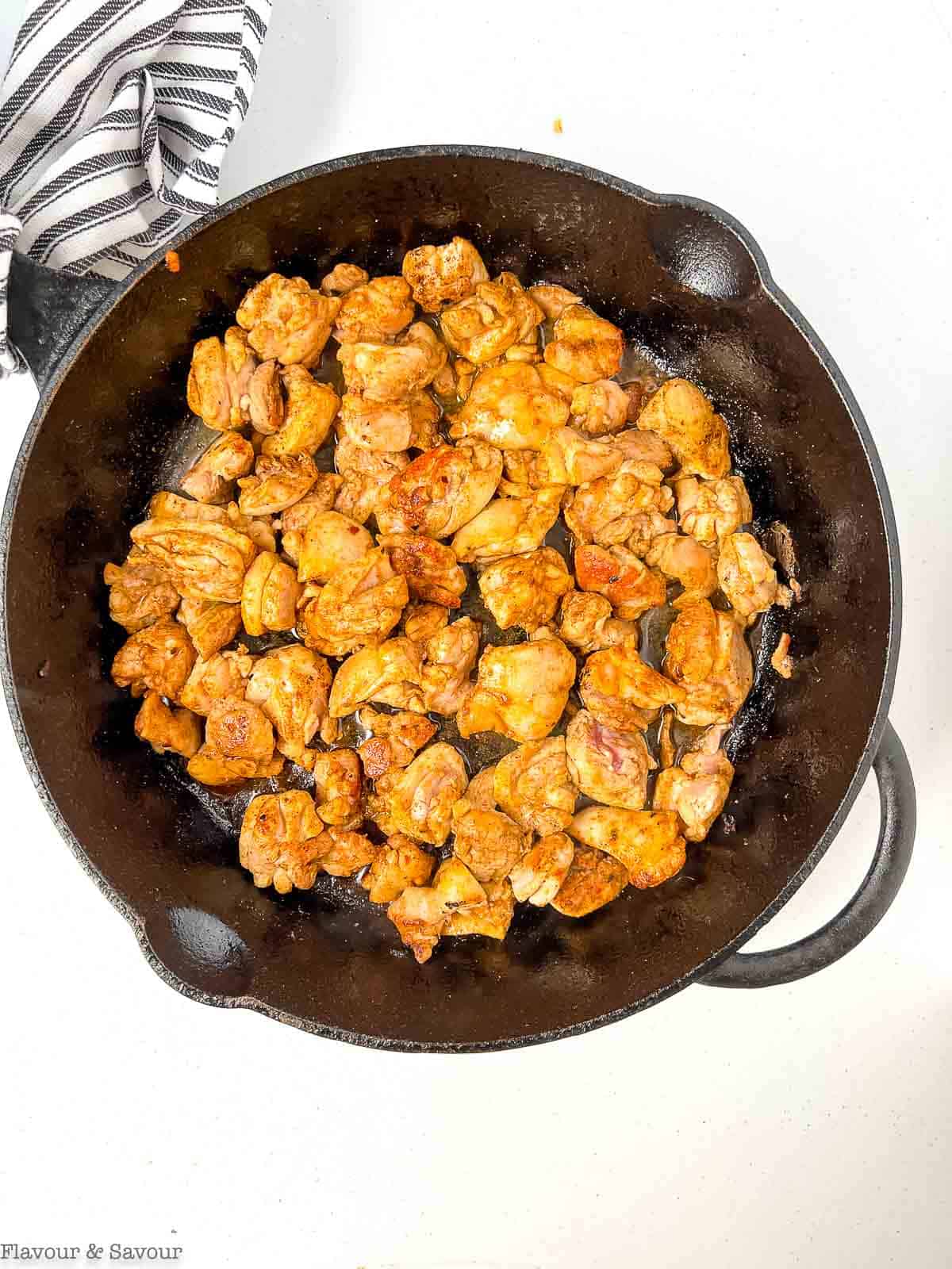 Browned chicken pieces in a cast iron skillet.