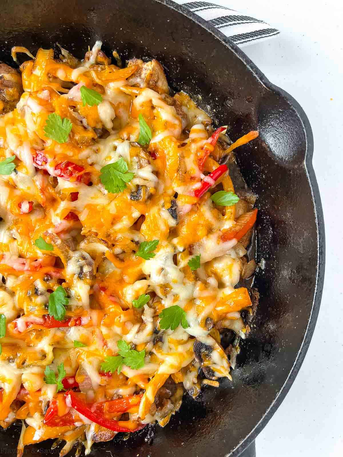 Close up view of a cast iron skillet with Baked Chicken Fajita Casserole.