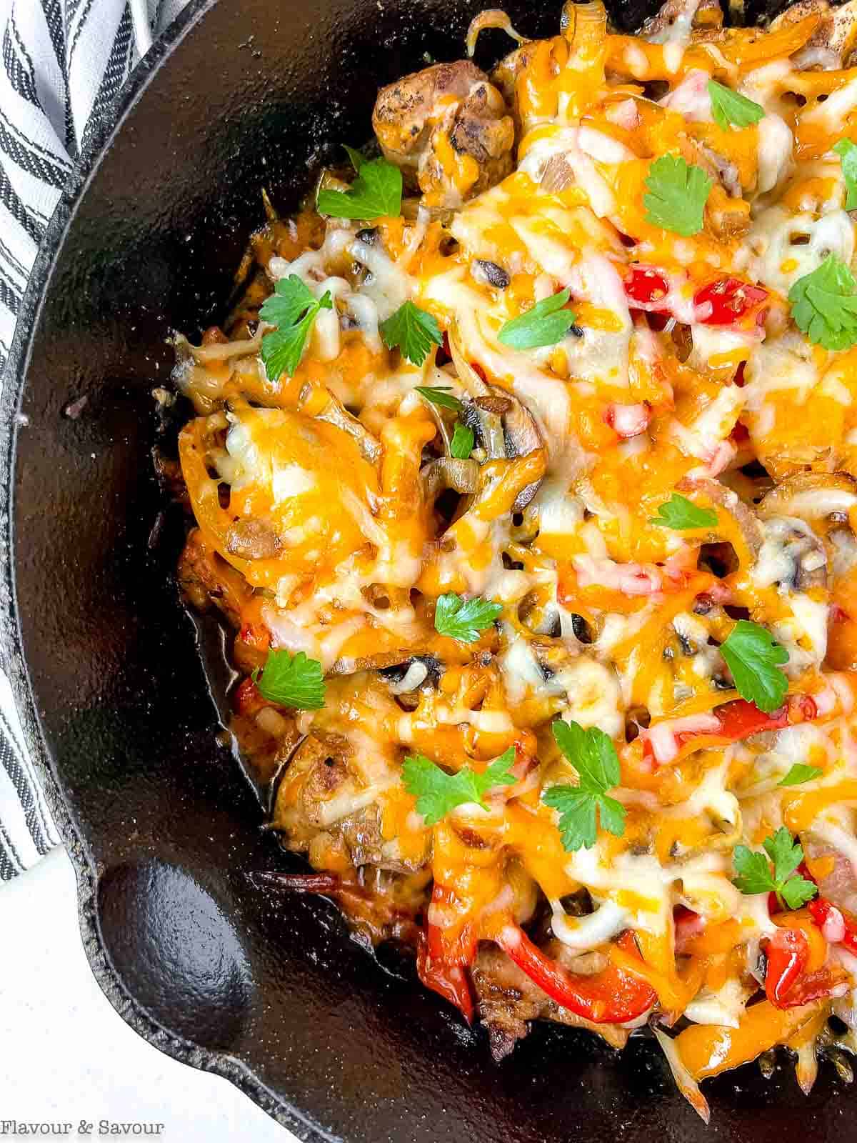 Close up view of baked chicken fajita casserole in a cast iron pan.