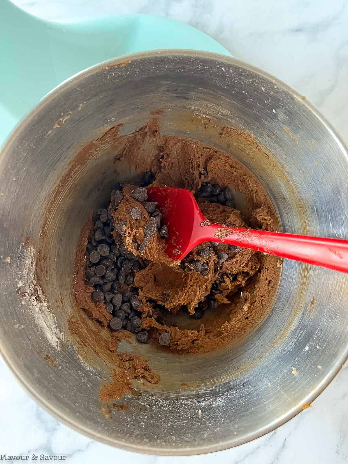 Adding chocolate chips to gluten-free chewy chocolate cookie dough.