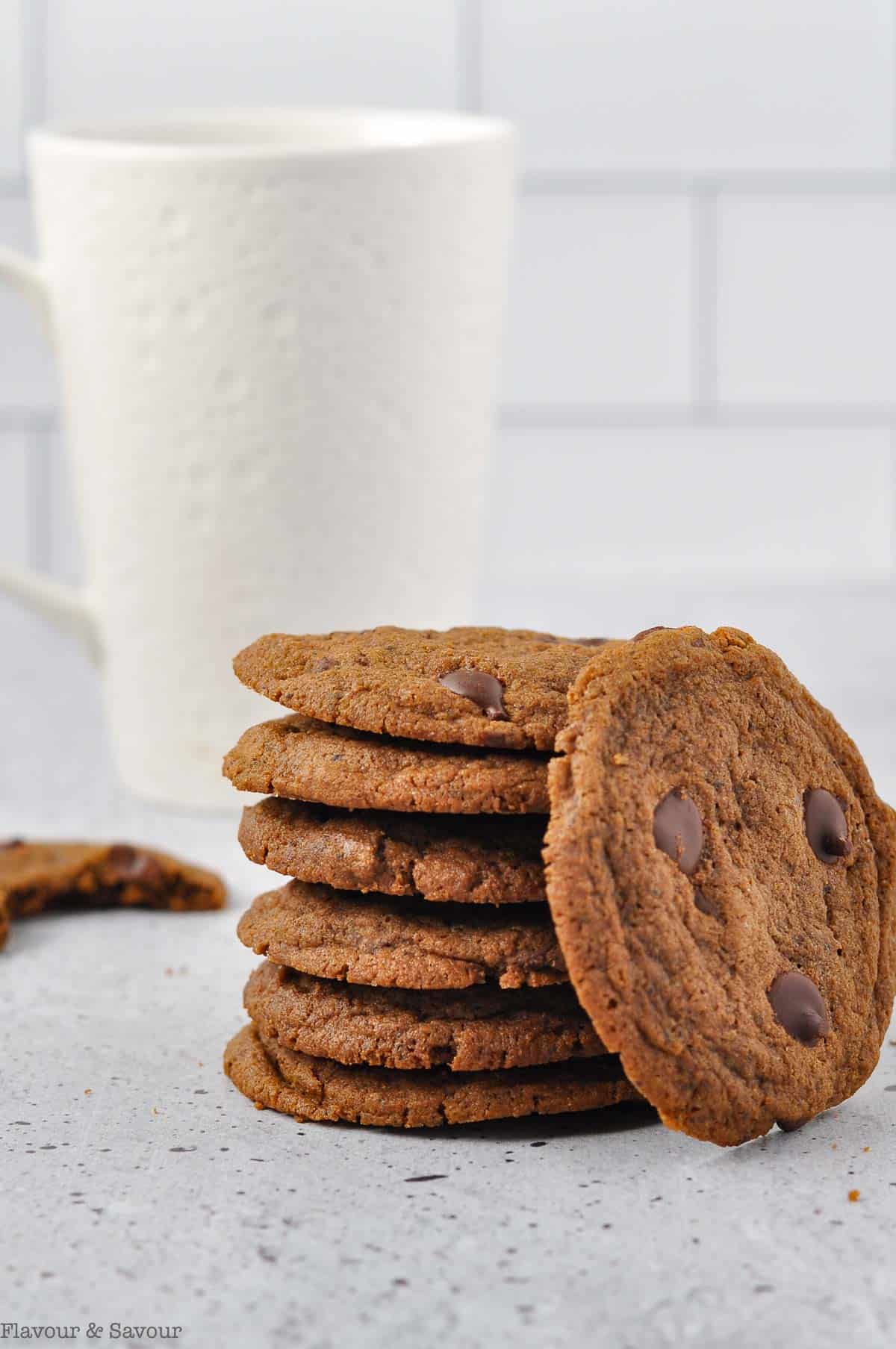 A stack of gluten-free espresso cookies with a white mug of coffee in the background.