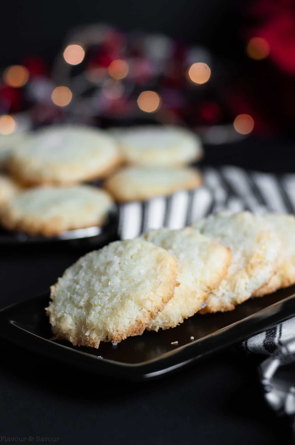 Crisp salted coconut cookies on a black serving plate.