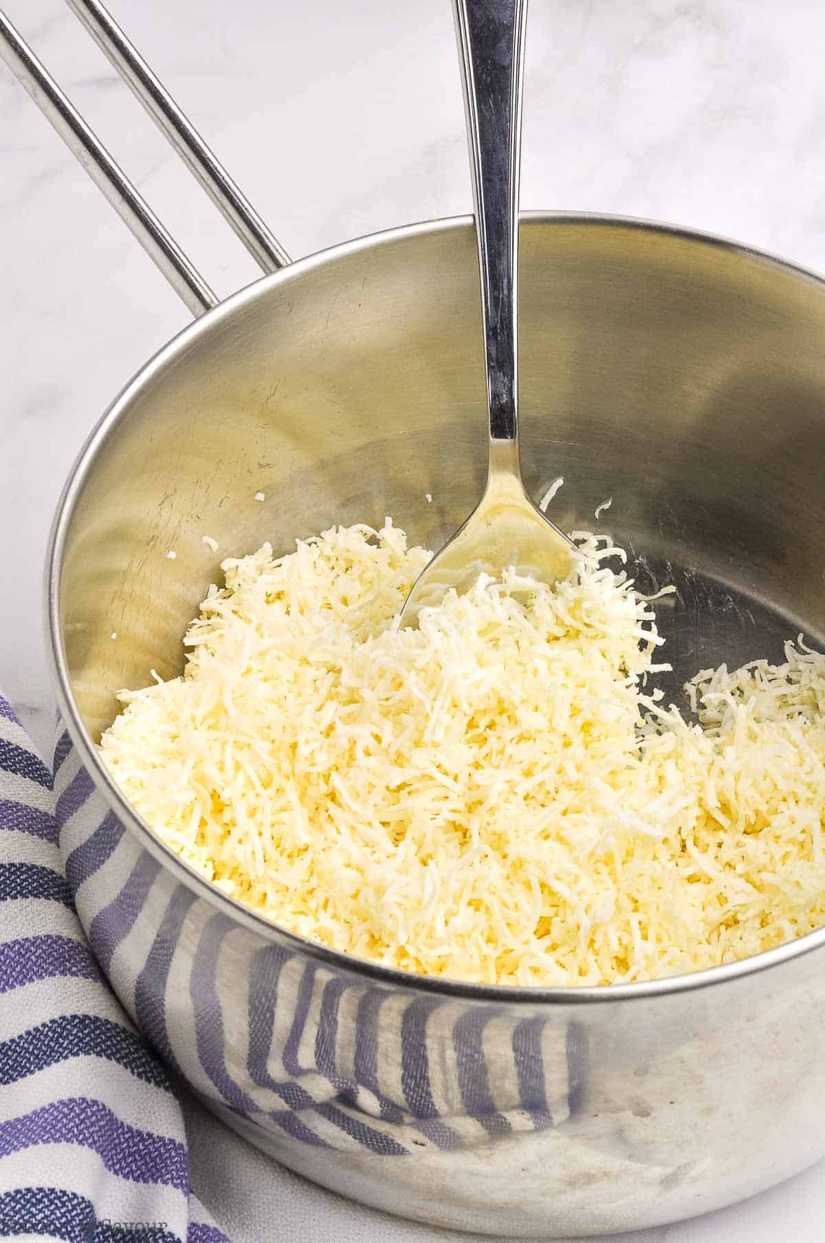 Stirring coconut with melted butter in a saucepan.