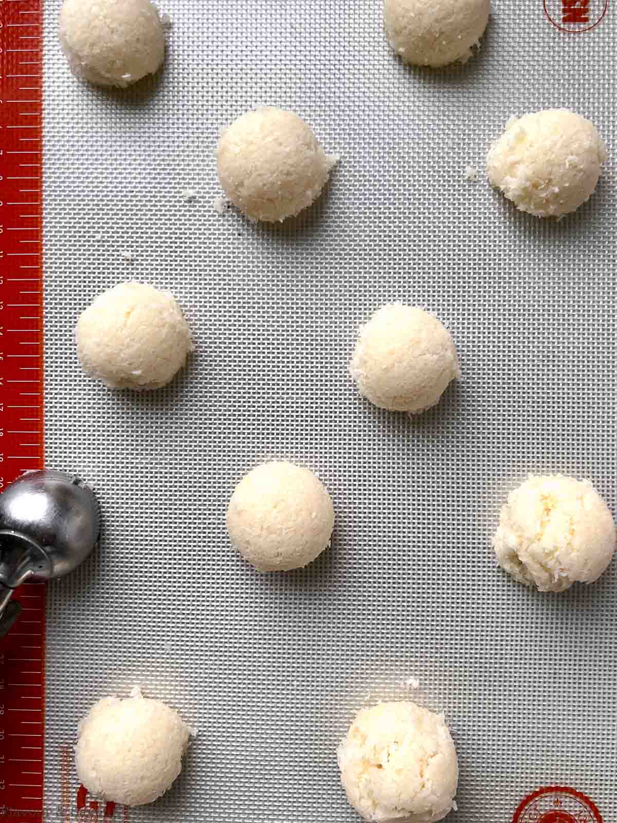 Using a cookie scoop to place coconut cookies on a baking sheet.
