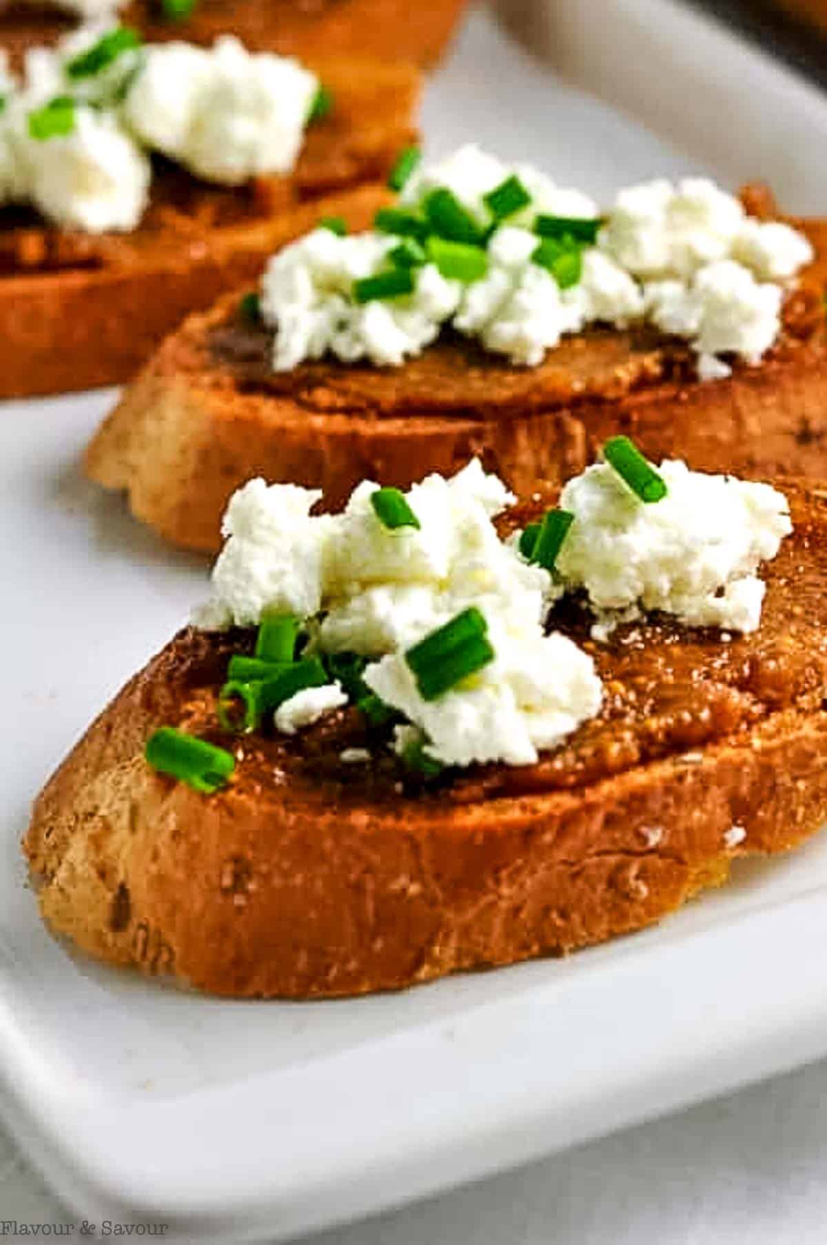 Close up view of two fig and goat cheese crostini appetizers.