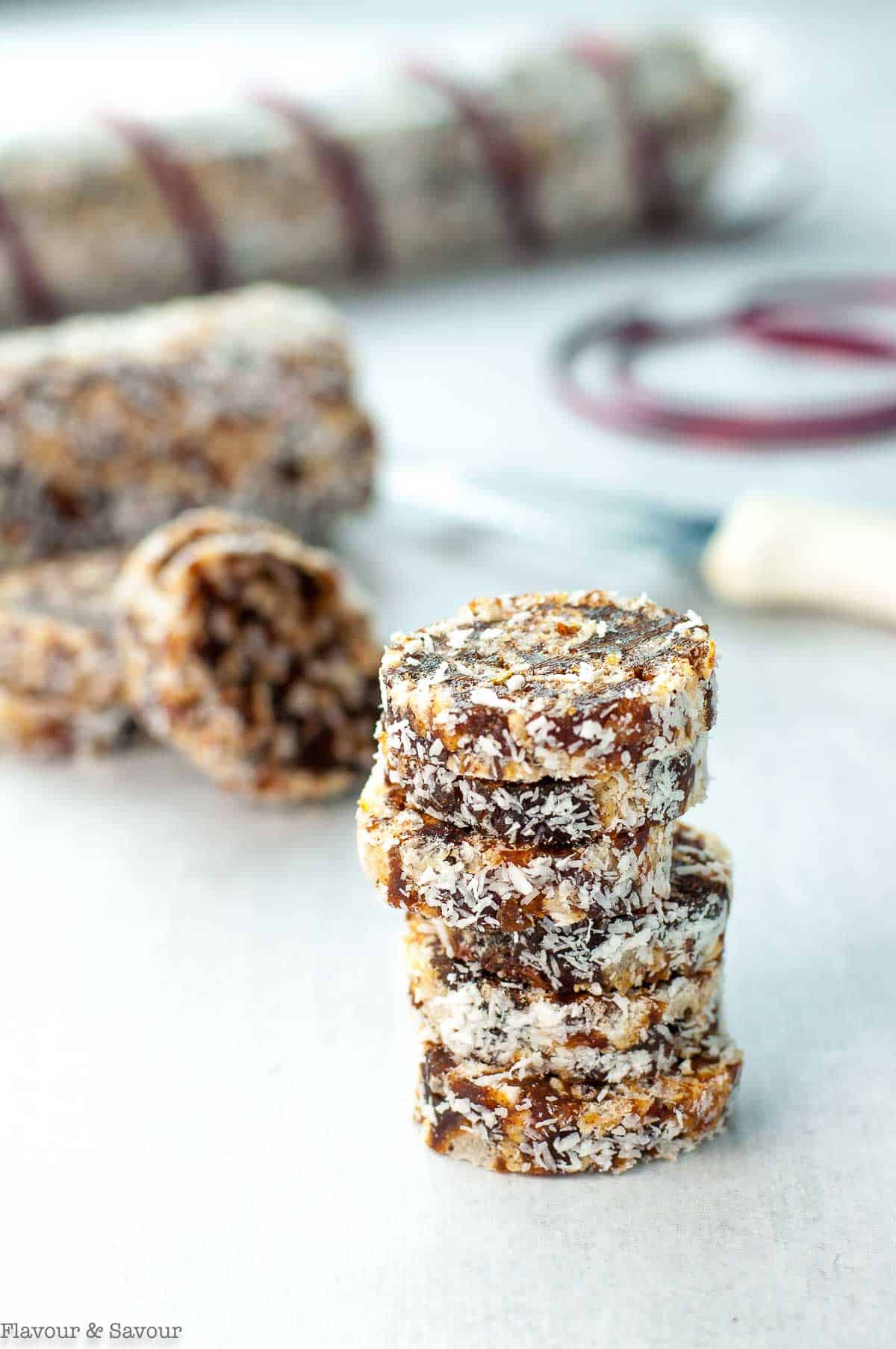 A stack of no-bake coconut date logs wrapped for a homemade food gift.
