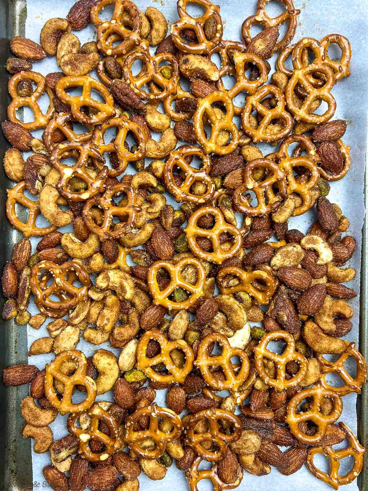 Pretzel and nut snack mix on a baking sheet.