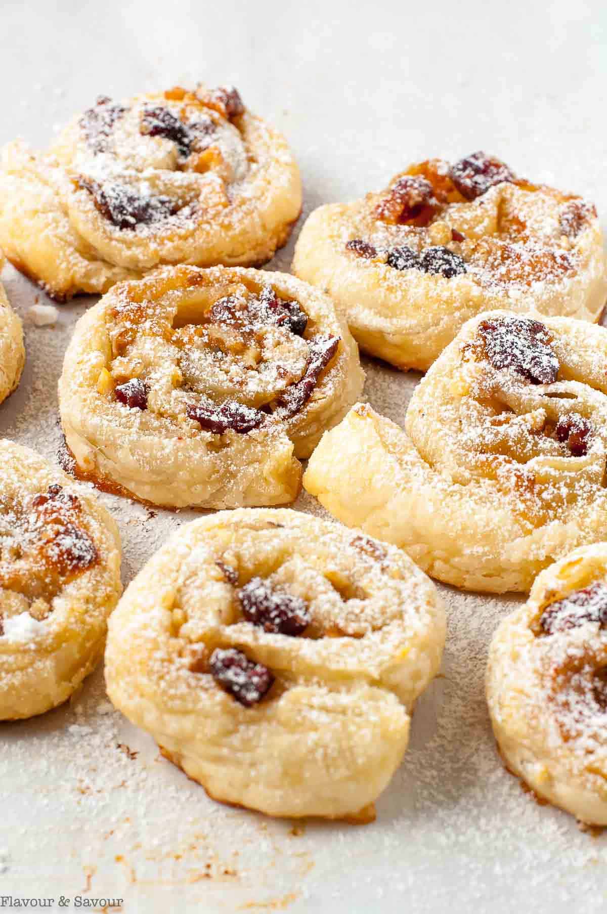 Puff Pastry Cranberry Brie Pinwheels on a baking sheet dusted with confectioner's sugar.