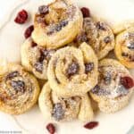Puff pastry cranberry brie pinwheels on a serving plate.