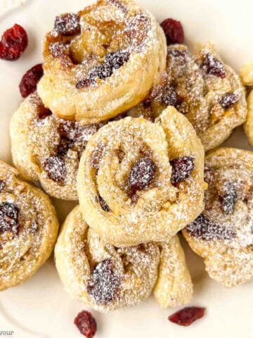 Puff pastry cranberry brie pinwheels on a serving plate.