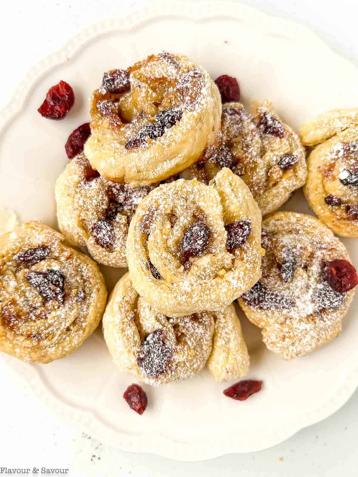 Puff pastry cranberry brie pinwheels on a serving plate.
