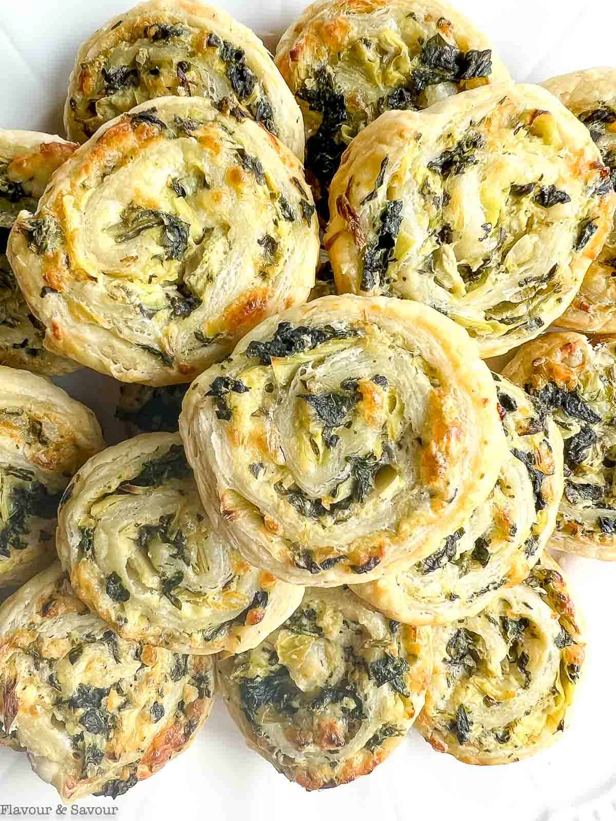 Close up view of crispy pinwheels made with puff pastry, spinach, cheese and artichokes.