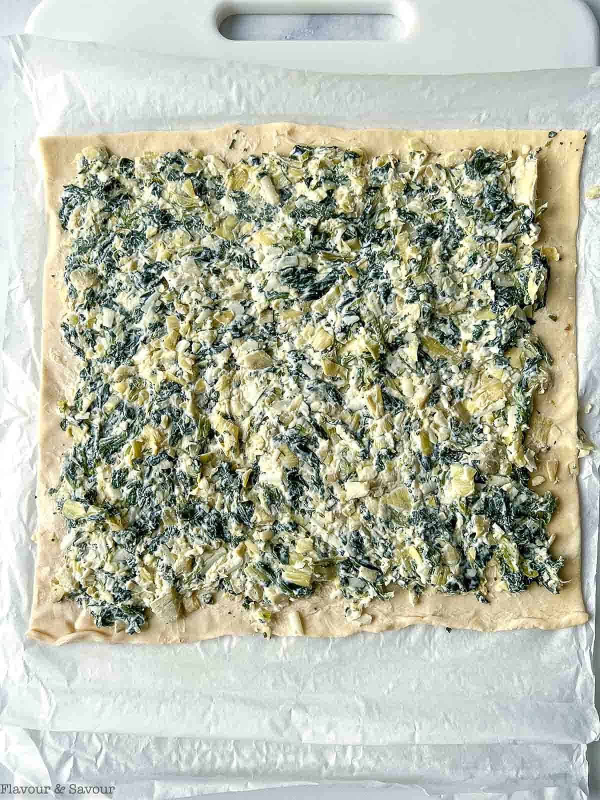 Puff pastry spread with spinach artichoke filling.