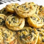 Spinach artichoke puff pastry pinwheels piled on a plate.