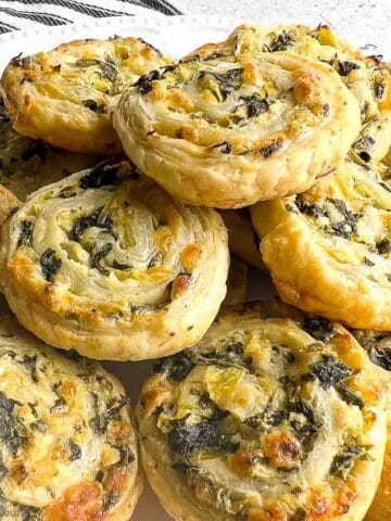 Spinach artichoke puff pastry pinwheels piled on a plate.