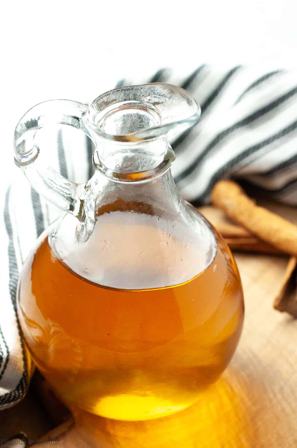 Cinnamon simple syrup in a cruet on a board.