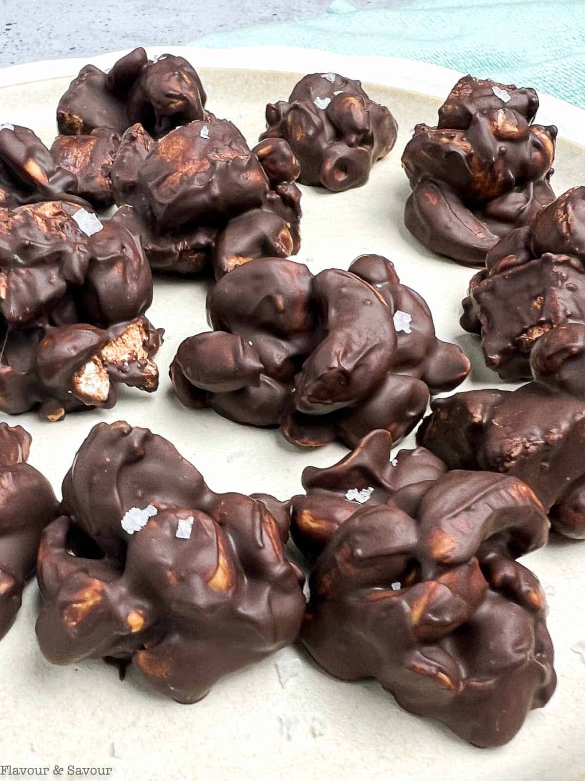 Close up view of chocolate covered cashew clusters made with cashews, peanuts and marshmallows.